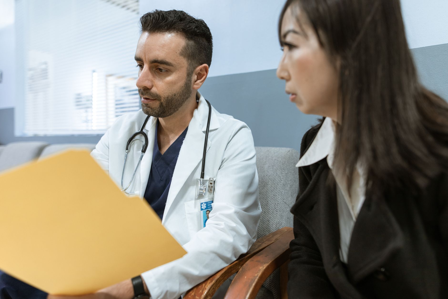 Médico conversa com paciente enquanto consulta registros de saúde em uma unidade clínica.