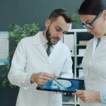 Médicos analisam uma radiografia exibida em um tablet durante atendimento em um consultório.