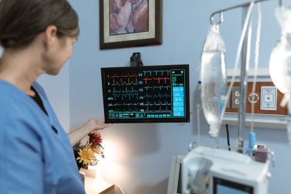 Profissional de enfermagem observa um monitor de sinais vitais em uma unidade hospitalar.