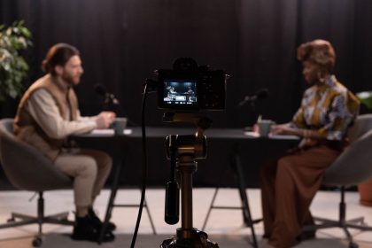 Dois apresentadores gravam um podcast em um estúdio equipado com microfones e outros aparelhos profissionais.